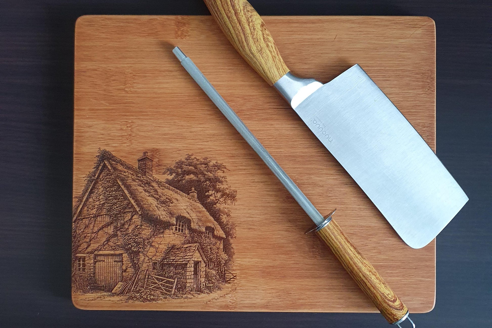 Wooden cutting board with engraved scene and two knives on a dark background