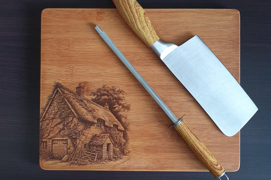 Wooden cutting board with engraved scene and two knives on a dark background